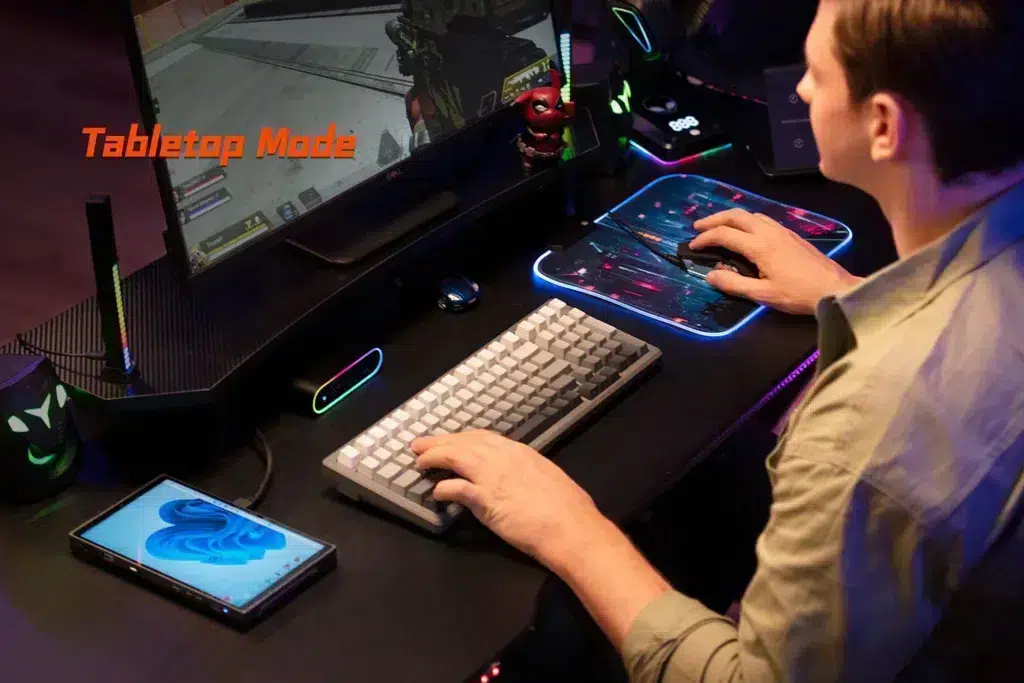 gempages_522757109238989843-8c2647f7-8344-424b-8670-20d83a53b2f8 - DROIX EU A user playing a first-person shooter on an external monitor connected to the ONEXPLAYER X1 Mini, showcasing its Tabletop Mode functionality for desktop-like gaming with a keyboard and mouse.