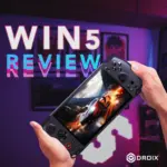 Una vivace immagine in miniatura per una videorecensione della console di gioco portatile GPD WIN 5. Un paio di mani tengono la console nera, leggermente inclinata verso lo spettatore. Sullo schermo viene visualizzata un'intensa scena di gioco di corse con un'auto incandescente. Lo sfondo è una stanza illuminata con accenti viola e neon. Un grande testo bianco con un effetto glitch rosa e blu sovrapposto sul lato sinistro recita "WIN 5 REVIEW". Il logo DROIX si trova nell'angolo in basso a destra.